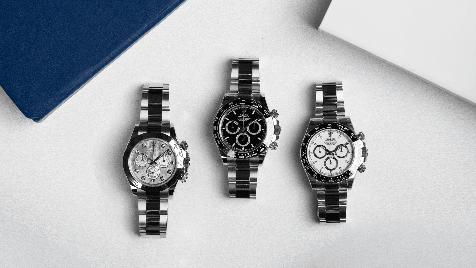 Three Rolex Daytona watches on a light surface